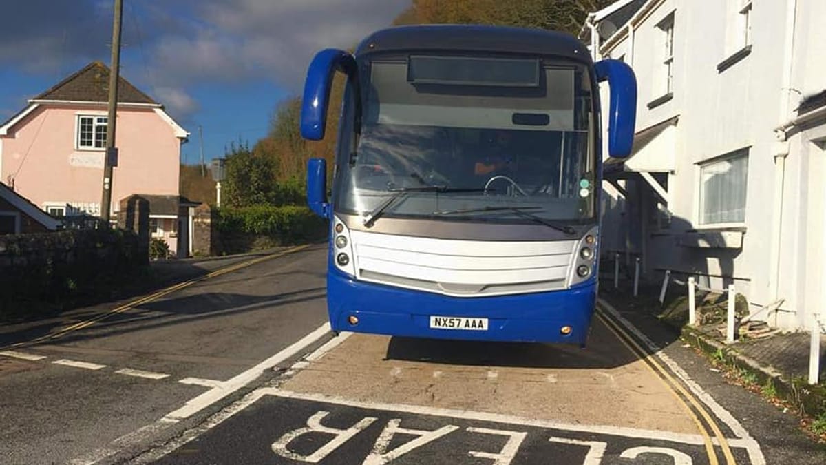 A coach carefully navigating a tight village road.