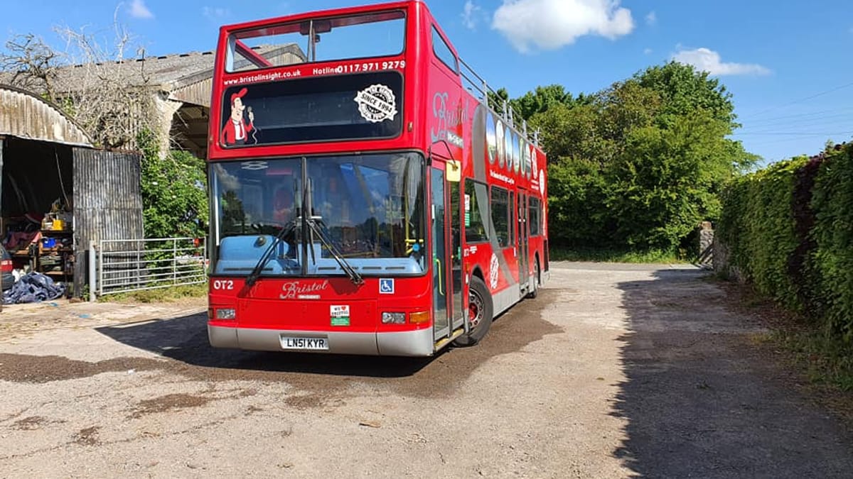 A red open-top double-decker bus parked in a depot yard.